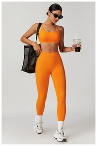 Detail of high-waist ribbed waistband on orange seamless yoga pants and sports bra set