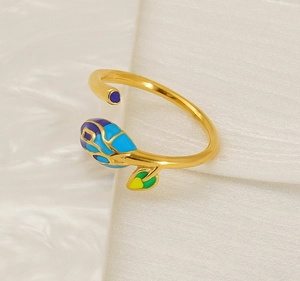 Macro shot of adjustable golden leaf ring with colorful floral enamel on white fabric