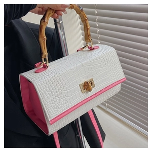 Detail of white crocodile texture handbag with pink trim and luxury bamboo handle