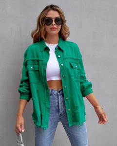 Detailansicht einer grünen Jeansjacke mit Distressed-Rissen und Fransen am Saum