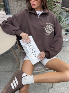 Detail of a brown half-zip sweatshirt featuring authentic society embroidery and textured cotton