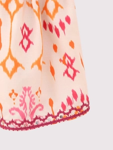 Détail du haut bohème avec broderie fuchsia et détails de paillettes argentées