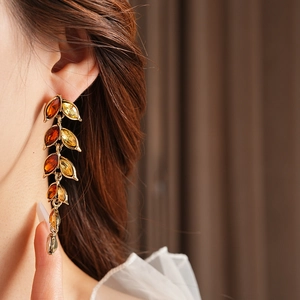 Gros plan de boucles d'oreilles feuilles dorées avec cristaux ambre sur le modèle