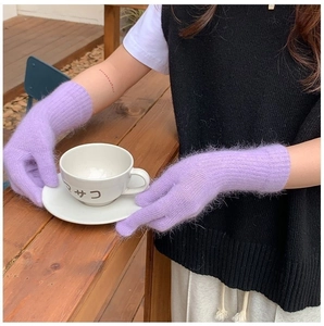 Close-up of thick purple faux fur knit gloves holding a white coffee cup outdoors