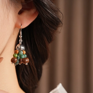 Macro detail of bohemian beaded earrings with wooden beads and turquoise stones on a model