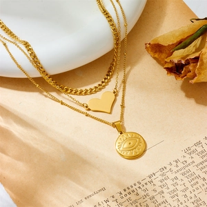 Detailed close-up of a layered gold necklace featuring heart and evil eye pendants