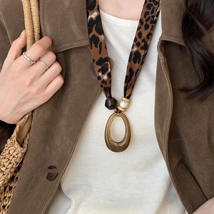 Detail of leopard print fabric strap and amber resin pendant on an ethnic necklace