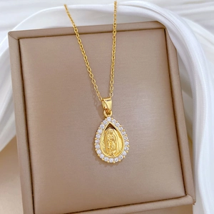 Gold titanium necklace featuring a teardrop religious pendant with zircons on silk background