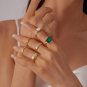 Close-up of gold rings set featuring emerald green stone and textured metal bands