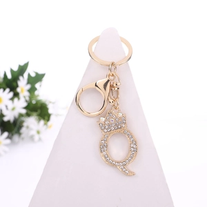 Golden crystal letter Q keychain with crown and clear rhinestones on white display stand