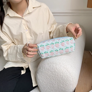 Detailed shot of quilted floral pencil case held by hand showing blue checkered pattern