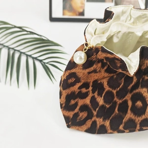 Detail of leopard print corduroy drawstring pouch with pearl charm and golden hardware