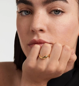 Detailed close-up showing the sleek golden wave ring design with polished metallic luster