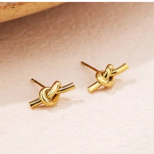 Macro view showing the intricate knotted design of these golden stainless steel stud earrings