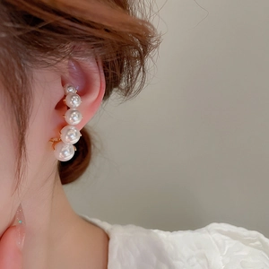 Detail of elegant French retro pearl ear climbers with five white pearls on gold plating