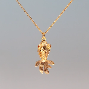 Macro shot of a vivid golden koi fish pendant with red eyes on a titanium steel necklace