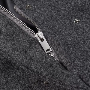 Dettaglio della cerniera metallica e della texture in lana grigio scuro sulla giacca moda