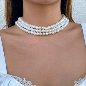 Detailed close-up of a three-layer pearl choker necklace featuring elegant gold spacers