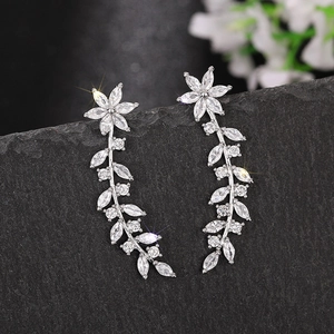 Macro shot of silver flower earrings with clear marquise zircon hanging on a dark rock