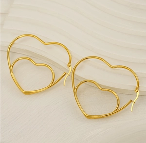 Detailed view of gold double layered heart hoop earrings on a white textured background