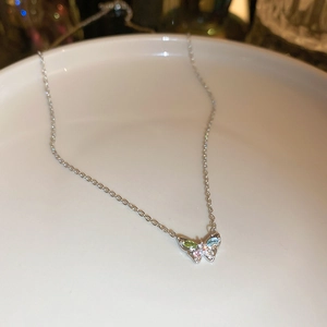 Detail shot of a butterfly pendant necklace featuring blue, pink, and green gemstones