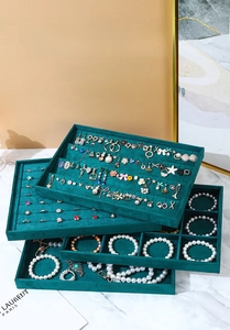 Detailed view of layered emerald green velvet jewelry trays with ring slots and grids