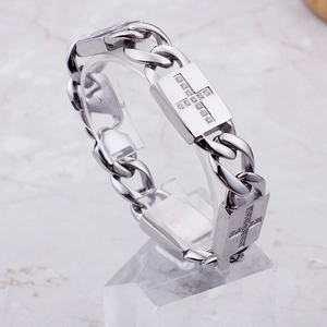 Détail d'un bracelet gourmette avec pendentif croix en argent et diamants sertis