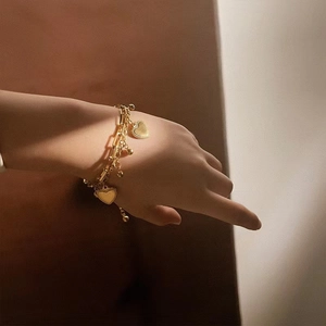 Elegant gold double-layered heart bracelet with beads on a wrist, stylish fashion jewelry