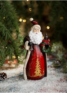 Detail of resin Santa Claus figurine with gold Christmas tree patterns and wreath