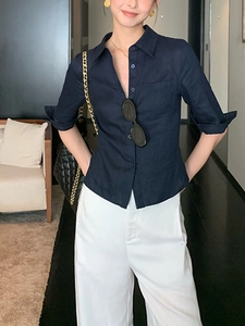 Détail de la texture d'une chemise en lin bleu foncé avec col boutonné et manches retroussées