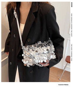 Detail of silver sequin handbag with thick metal chain and leather strap on model