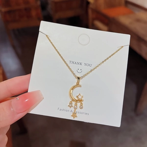 Detail of gold-plated moon and star pendant with cubic zirconia on a display card
