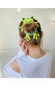 Detailed back view of a model wearing a green plush frog hair tie on a bun