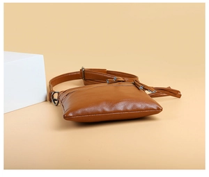 Detail view of brown pebbled leather crossbody phone bag with zipper and tassel puller