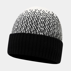 Detail of winter beanie featuring black ribbed cuff and black and white knit pattern