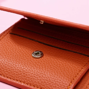 Detailed macro view of orange leather wallet interior showing card slots and snap fastener