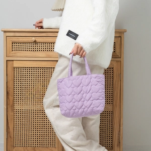 Close-up of lavender quilted handbag with heart pattern shown in a cozy home setting