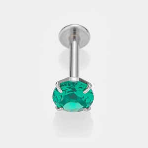 Macro di un piercing al labbro in acciaio al titanio con zirconia verde a quattro griffe