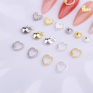 Macro shot of gold and silver heart-shaped 3D nail art charms on manicure