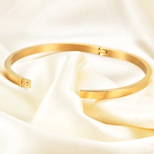 Minimalist 4mm gold stainless steel open bangle for women on beige silk fabric