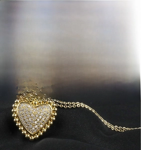 Macro view of gold heart pendant with cubic zirconia micro-pave setting on black fabric