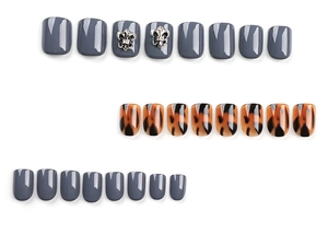 Detail of dark grey press-on nails with leopard print and silver vintage floral charms