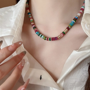 Close-up of a multi-colored beaded necklace with 18k gold accents worn on a model neck
