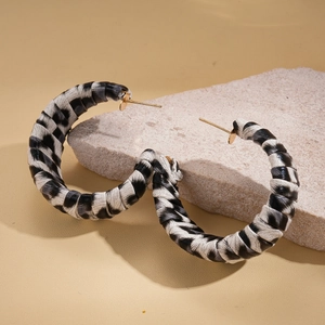 Macro shot of geometric C-shaped earrings with black and white leopard pattern leather wrap