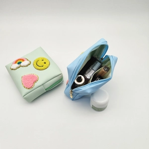 Detail of cute makeup bag with plush patches and open zipper showing storage space