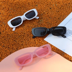 Dettaglio di occhiali da sole rettangolari per bambini nei colori bianco, nero e rosa