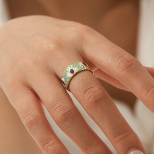 Macro shot of gold Evil Eye ring featuring colorful enamel details on a female hand