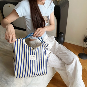 Detail of yellow and blue striped canvas tote bag with woven texture in a home setting