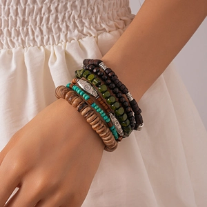 Detail of bohemian multilayer bracelets with wooden beads and engraved sun charm