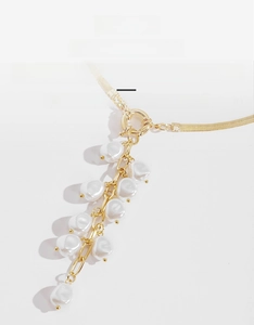 Detailed macro view of baroque pearl tassels and golden flat snake chain necklace